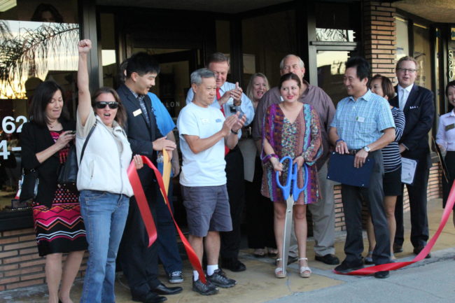 IMG_2585 a group of people stands beside a woman holding a large pair of scissors and there is a cut ribbon on the ground