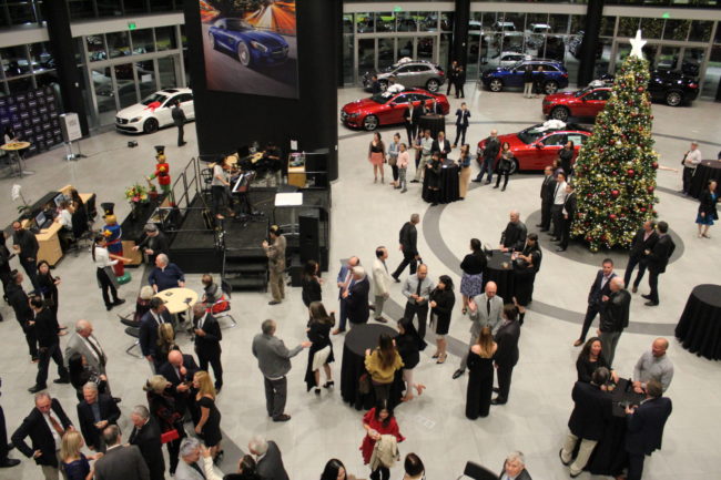 IMG_5249 a group of people in an automobile showroom with a christmas tree