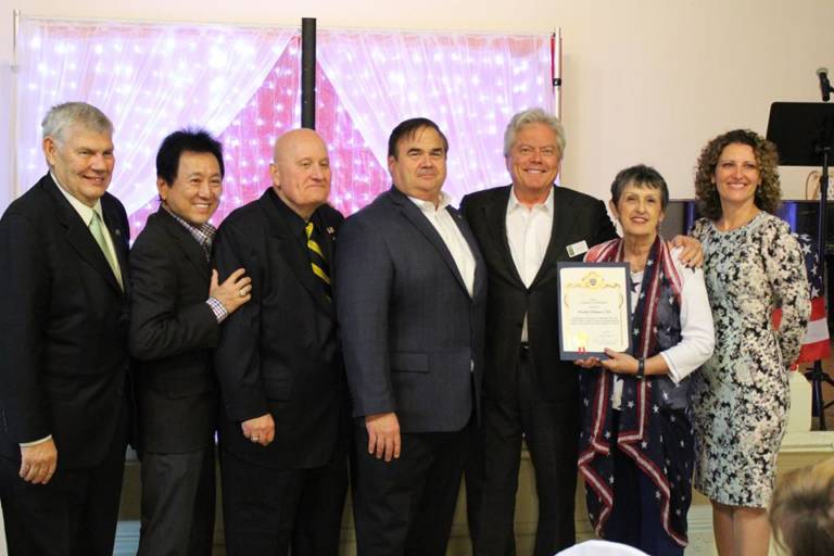 two women standing with a group of men and one of the women is holding a certificate