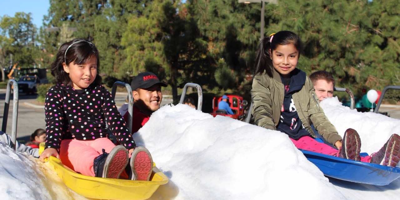 two young girls on sleds ready to slide down a hill of snow