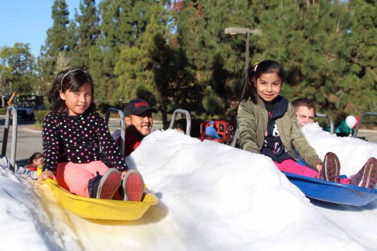 two young girls on sleds ready to slide down a hill of snow