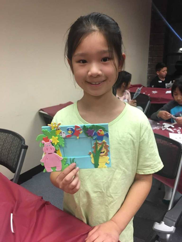 a young girl holding up a homemade picture frame