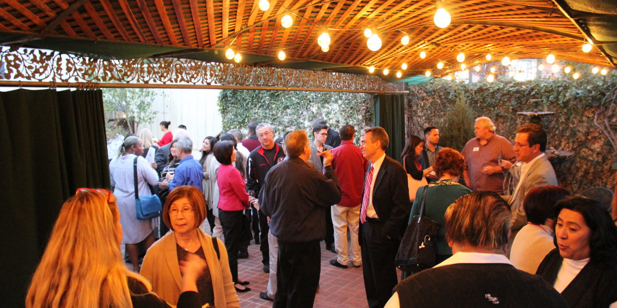 a gathering of people on a patio under a canopy with lights