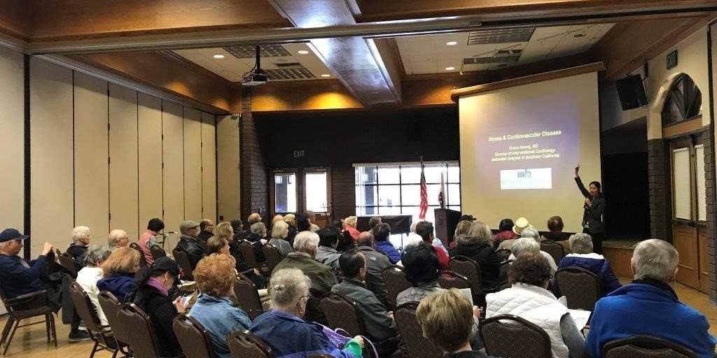 a room full of people looking at someone giving a presentation on a projector screen