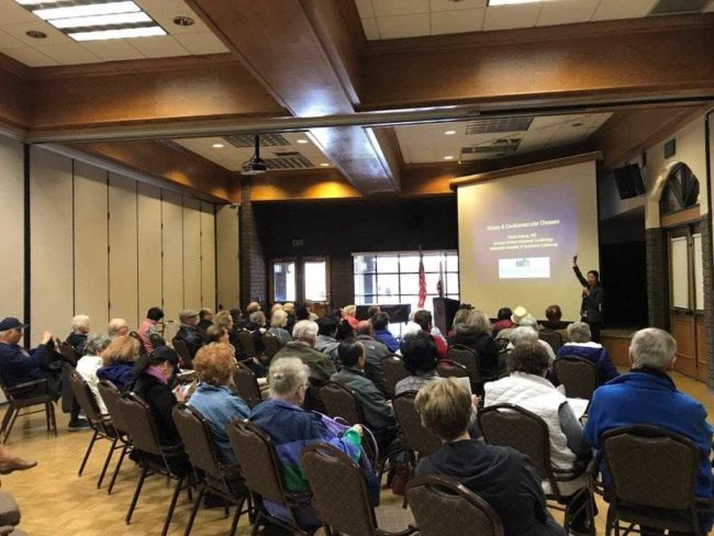 a room full of people looking at someone giving a presentation on a projector screen