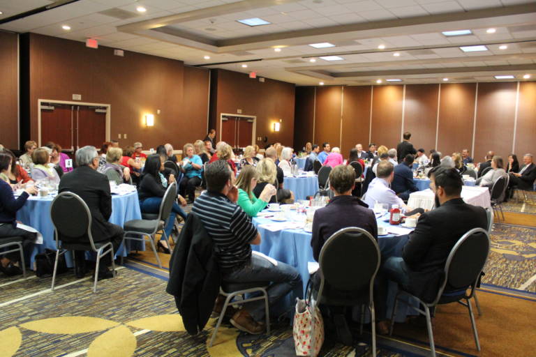 a room full of people seated at round tables