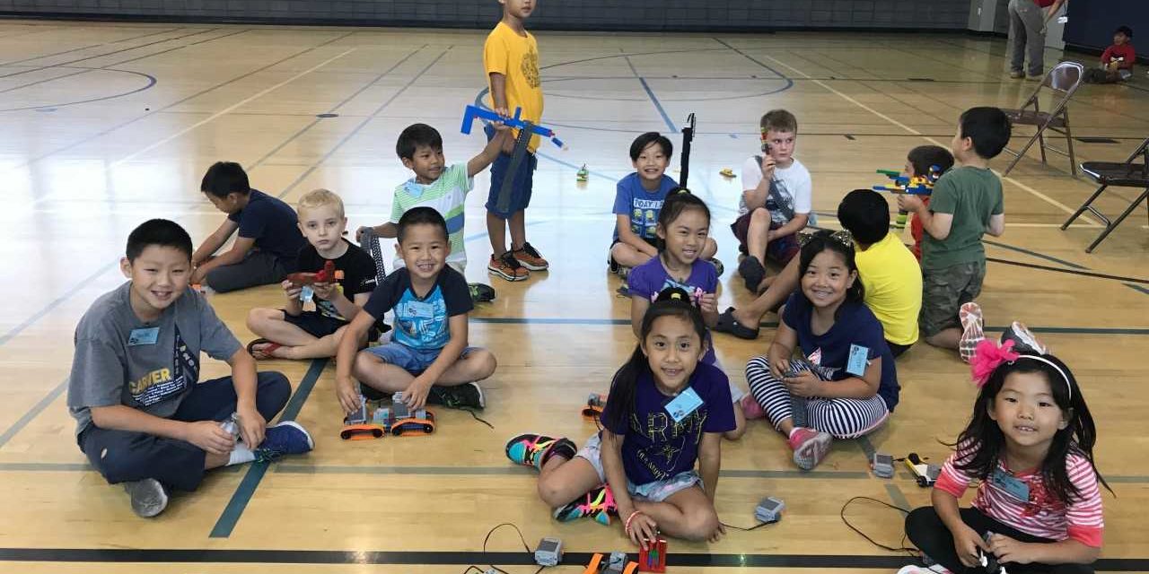 a group of children seated on the floor of a basketball court