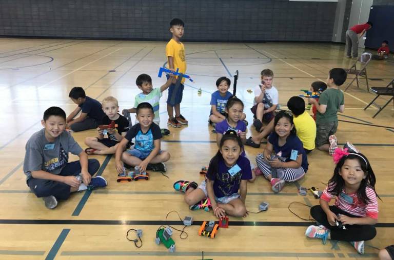 a group of children seated on the floor of a basketball court