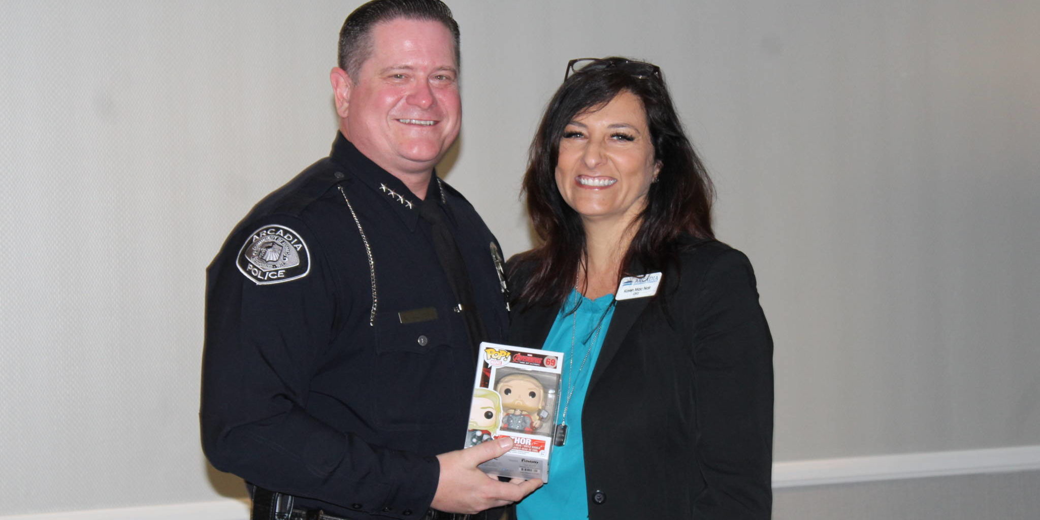 a man in uniform holding a pop figure and standing next to a woman in a blue shirt and black jacket