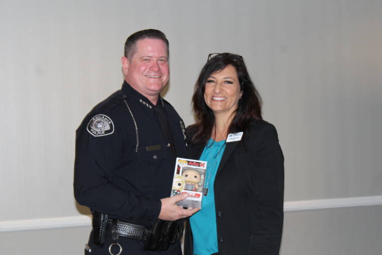 a man in uniform holding a pop figure and standing next to a woman in a blue shirt and black jacket
