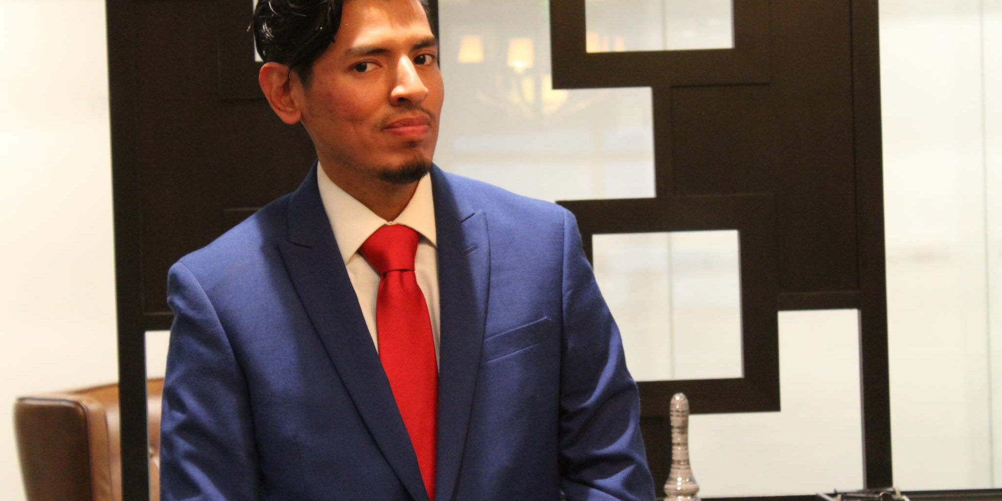 a man in a blue suit looking suave with a red tie