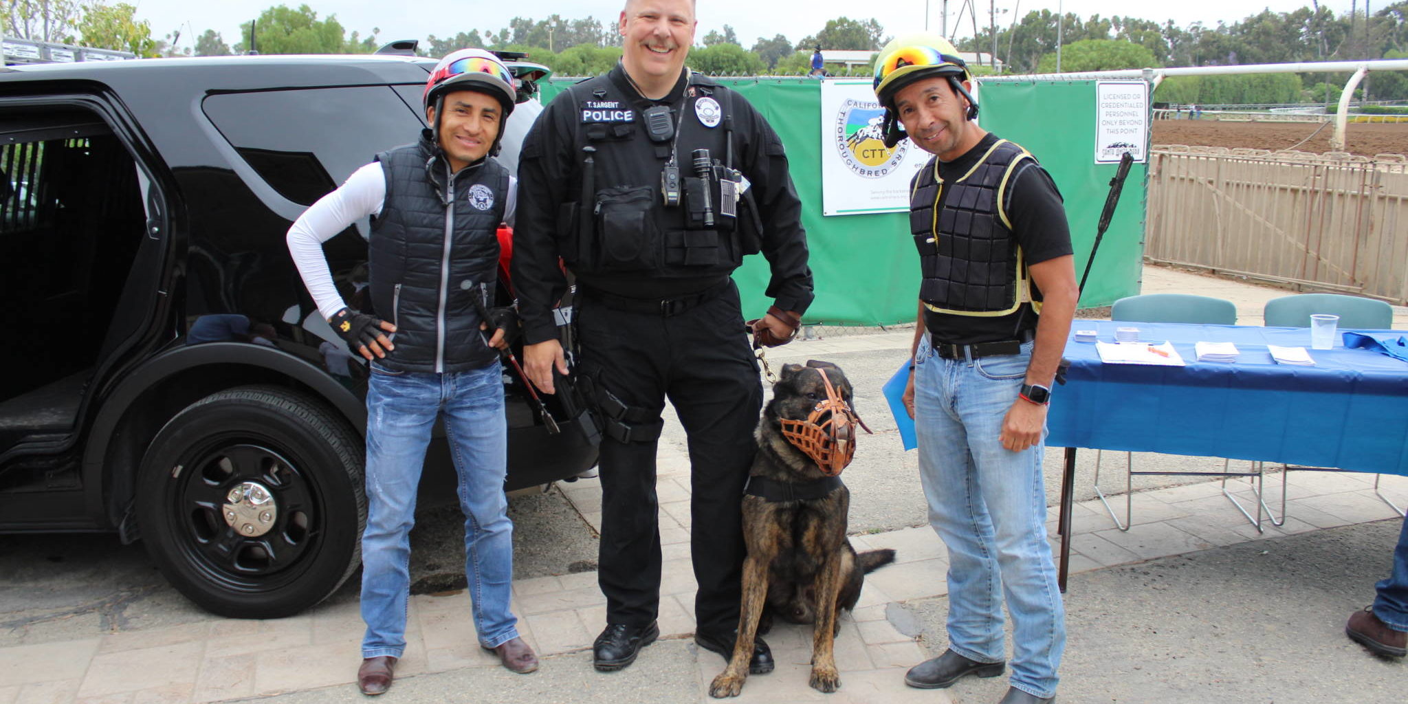 a man in a police uniform with his police dog standing between two jockeys