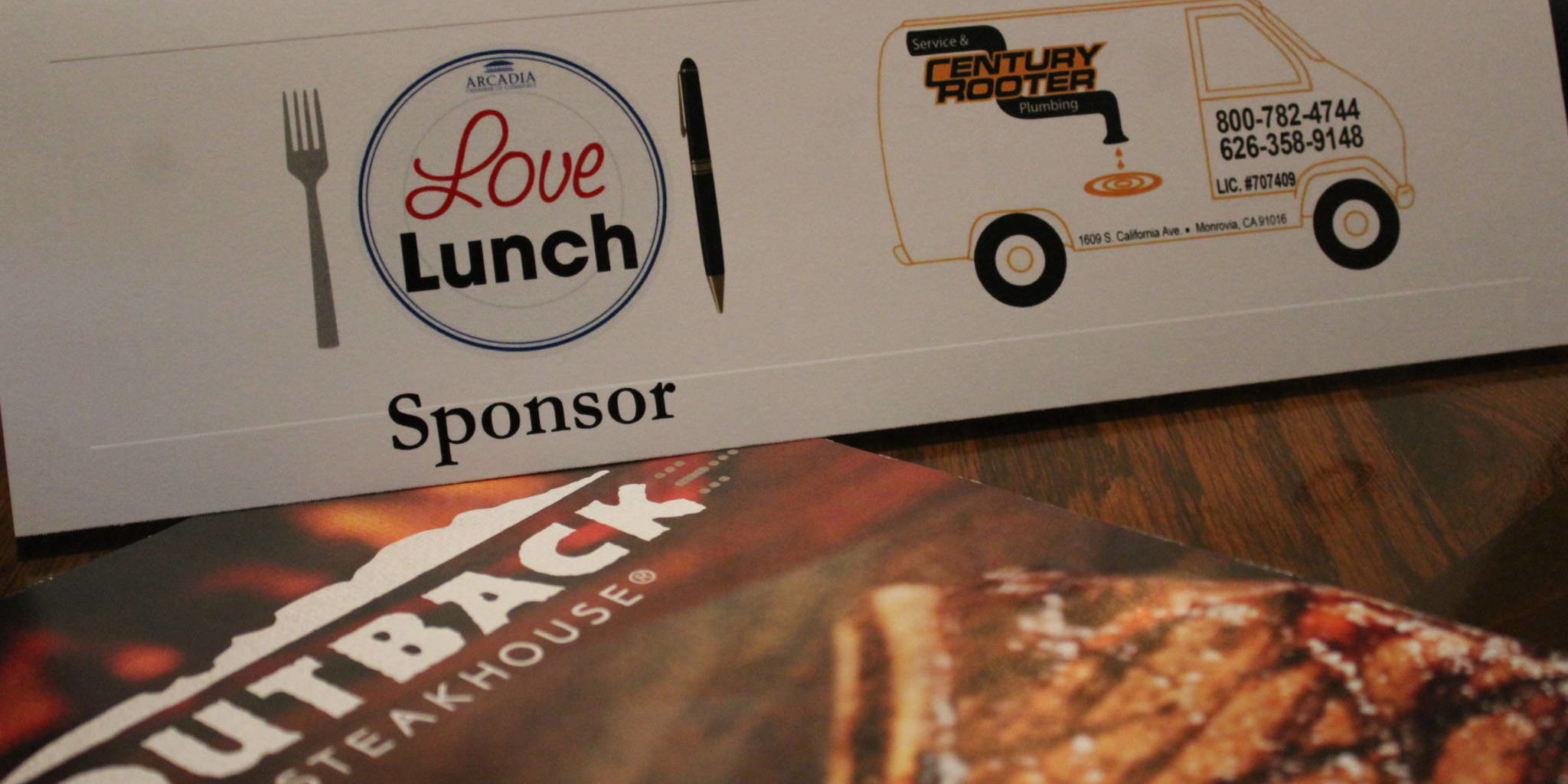 IMG_5880 love lunch sponsor tent card for Century Rooter on top of a menu for Outback