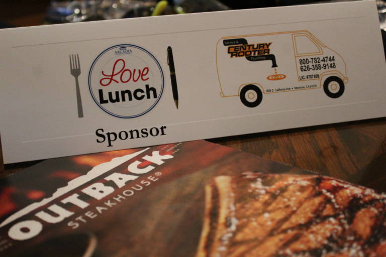 IMG_5880 love lunch sponsor tent card for Century Rooter on top of a menu for Outback