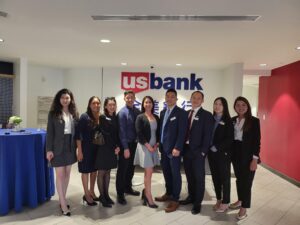 a large group of men and women standing in front of the US Bank logo 