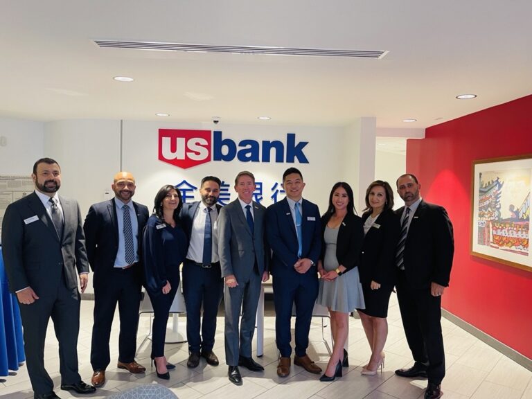 a group of people standing in front of a sign for US Bank