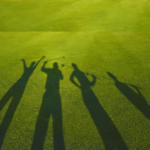 Four golfers with their shadows only showing on the grass