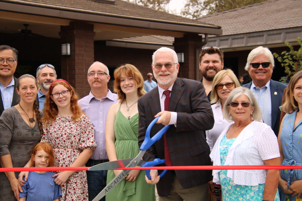 a group of people holding large scissors at a ribbon cutting