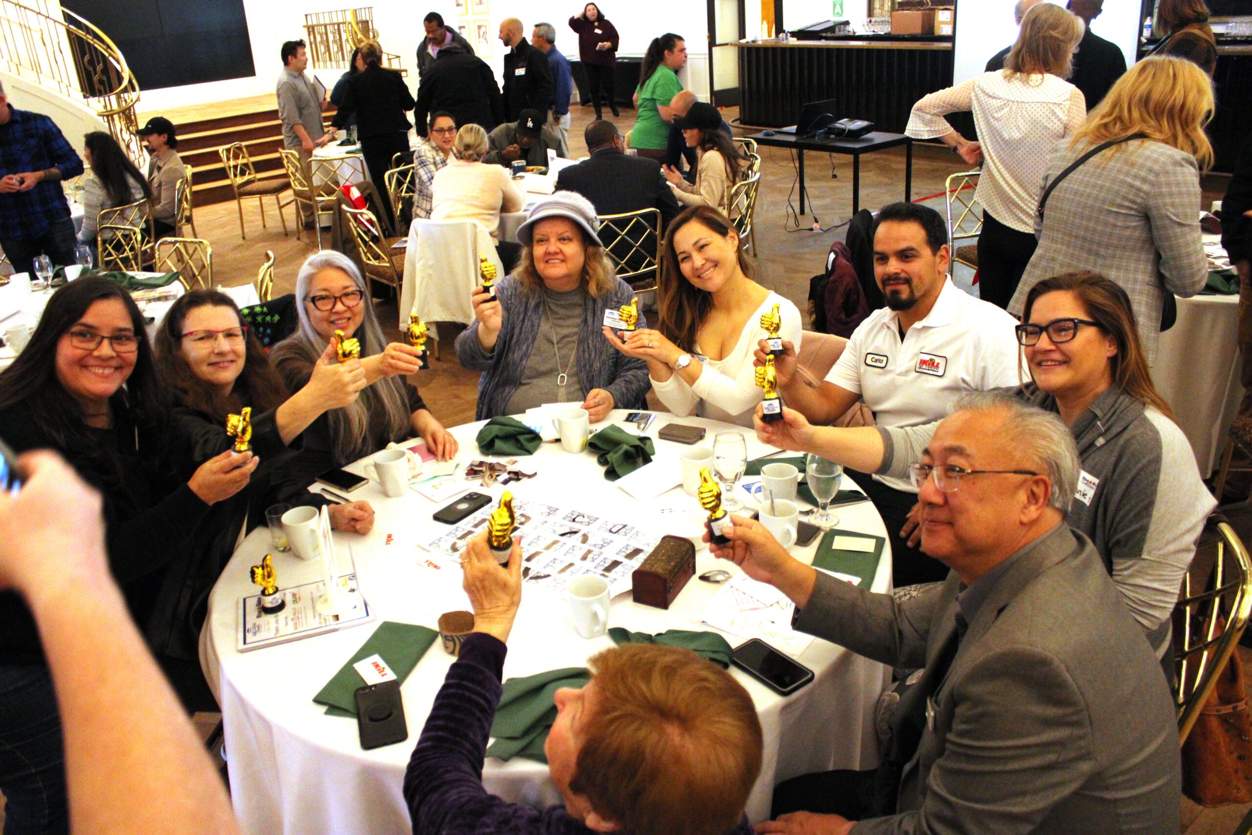 a group of people at a table holding up trophies at a Rise & Shine breakfast