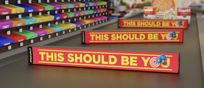 a grocery store check out lane with dividers advertising 'this should be you' sales