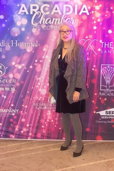 a woman in a gray jacket and pants standing in front of a colorful stand and repeat