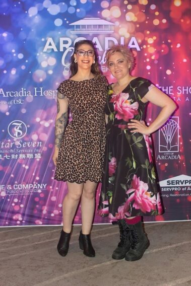 a woman in a leopard print dress standing with her arms around a woman in a black and pink floral print dress