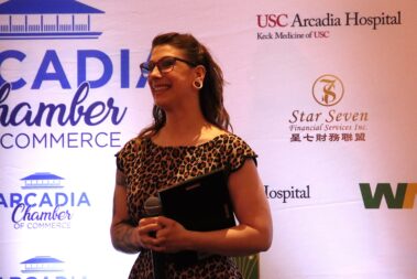 a woman in a leopard print dress smiling while holding a plaque
