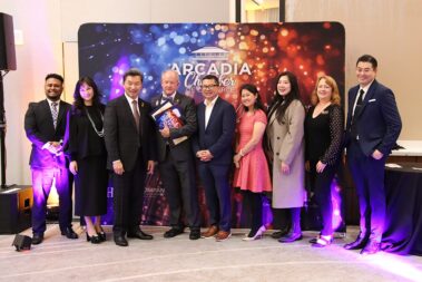 a large group of people standing in front of a colorful step and repeat, with the man in the center holding plaques and certificates