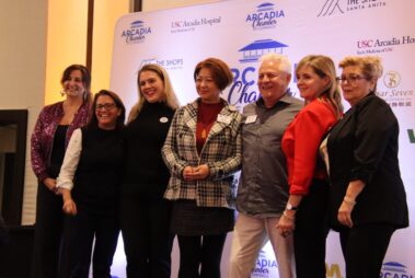a group of women and men posing in front of a step and repeat banner