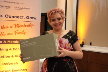 a woman with short, pink hair holding a box containing a massager from OSIM