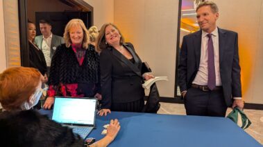 a woman at a check in table smiling at the camera
