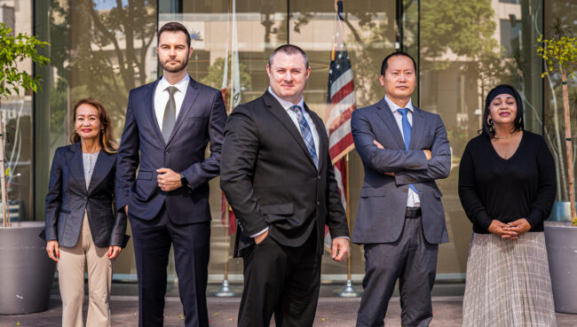 Doyle Law Firm lawyers standing in a line in front of a window