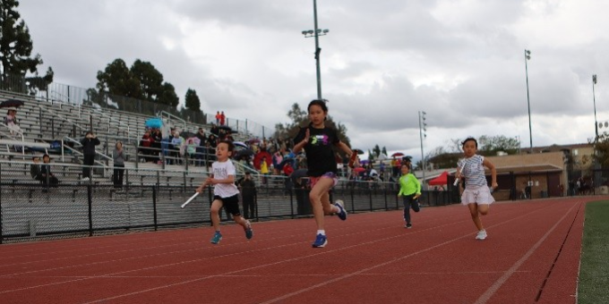 city of arcadia track meet four young people compete on a track with a cloudy sky above them