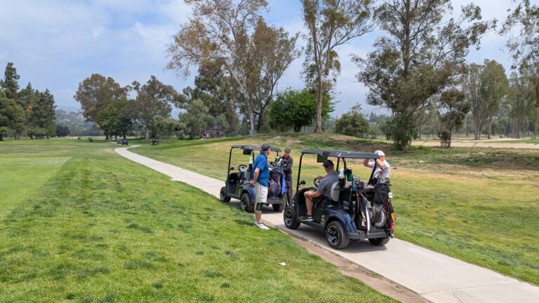 two golf carts on a cart path driving away from the camera
