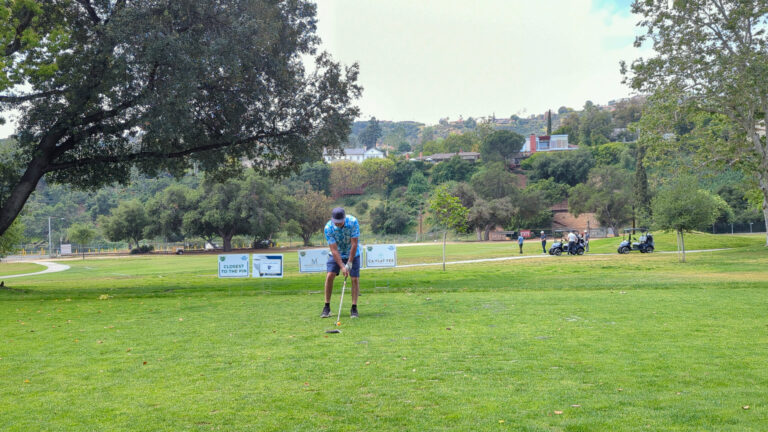 a man in a blue shirt getting ready to tee off on the golf course