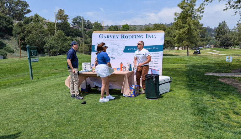 a woman in a blue shirt and white skirt standing in front of a booth for Garvey Roofing