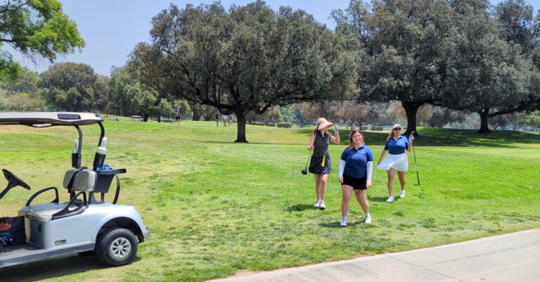 a group of three golfers posing for the camera near their golf cart