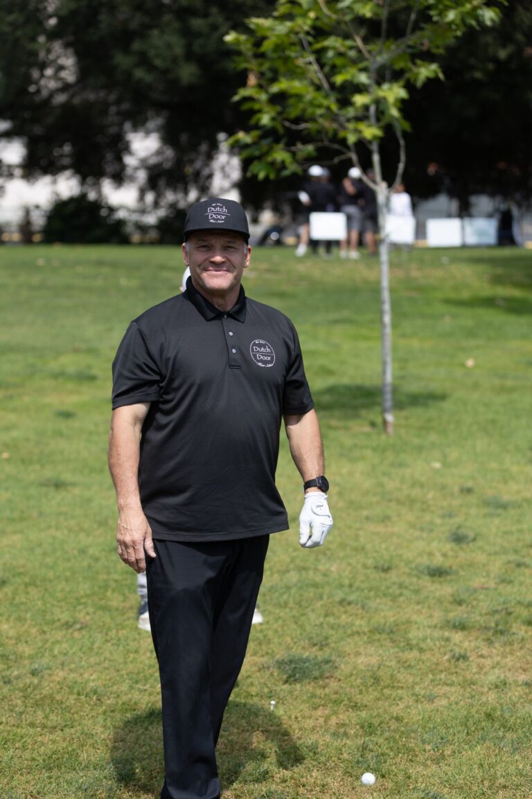 a man in all black poses in his golf gear