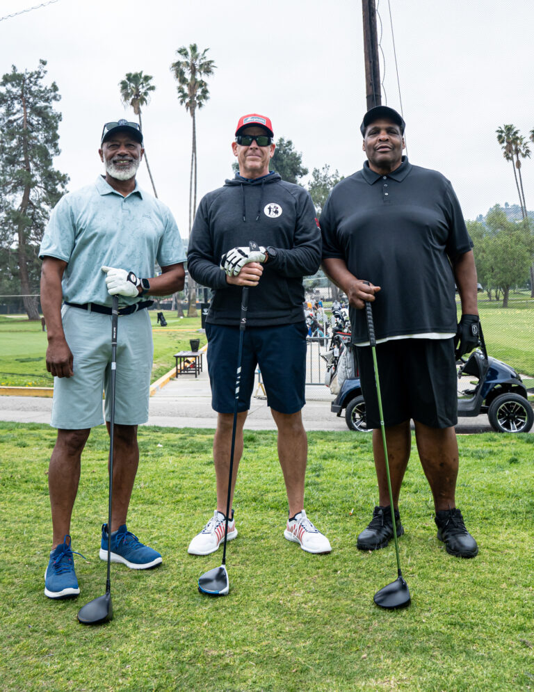 a group of three golfers posing with their golf clubs