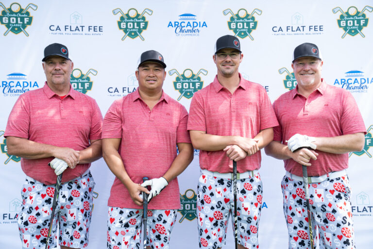a group of four golfers in matching pink shirts and colorful golf shorts from the David Mac Nair team