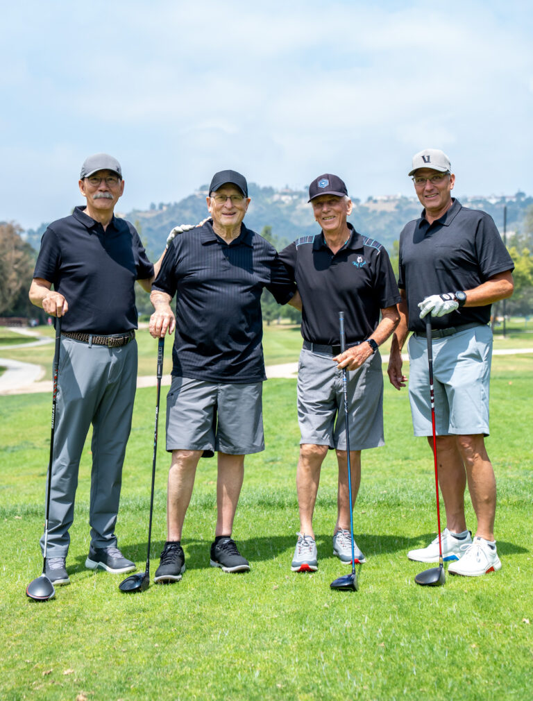 a group of four golfers from the Neil Bradley Team all in black attire