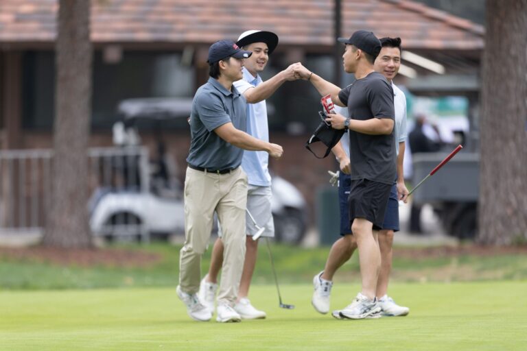 a group of male golfers fist bump each other after making a putt