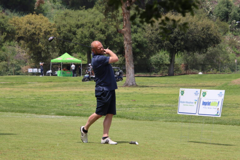 a man in blue teeing off at a golf tournament