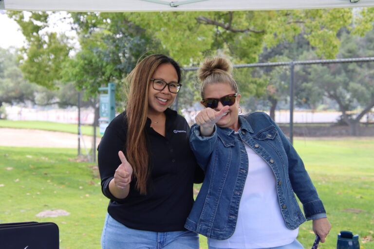 two women giving a thumbs up towards the camera on a golf course