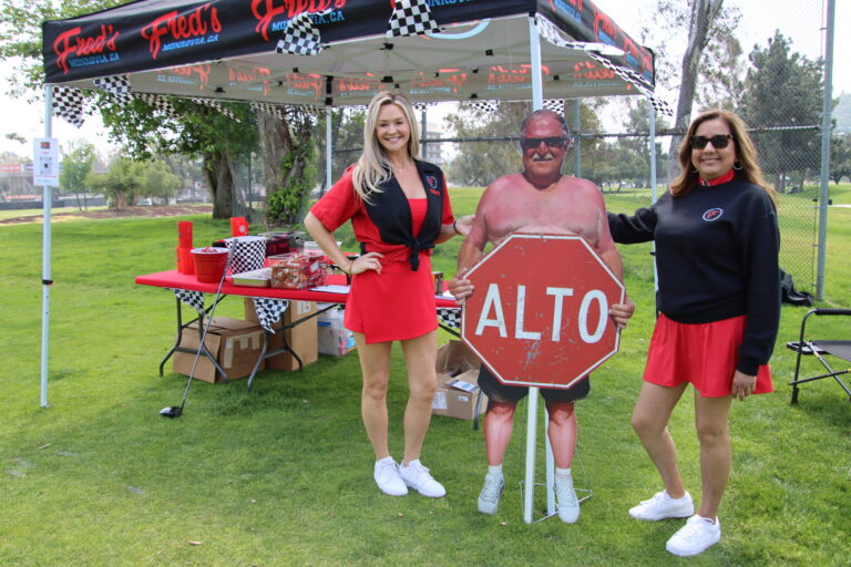two women standing on either side of a cardboard cutout of a man holding a stop sign