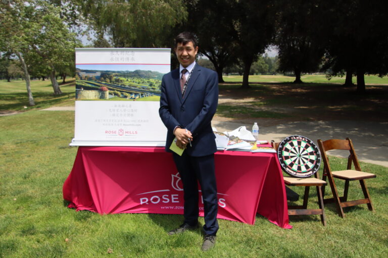 a man in a suit stands behind a table set with items from Rose Hills