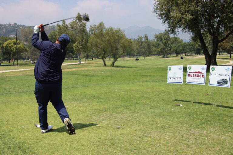 a man in all blue tees off next to a row of tee signs