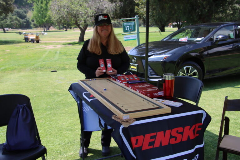 a woman standing in front of a shuffle board on top of a table set with a Penske table cloth