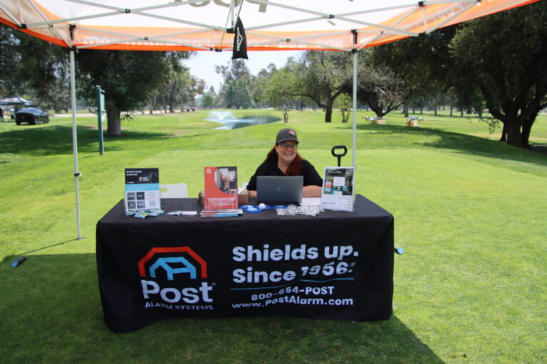 a woman in black baseball cap sits at a table set with a Post Alarm table cloth