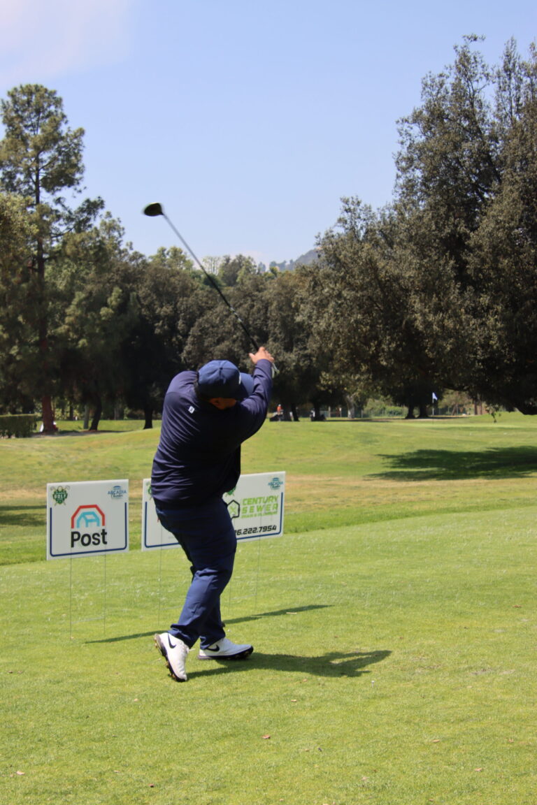 a man in all blue tees off in front of a row of tee signs